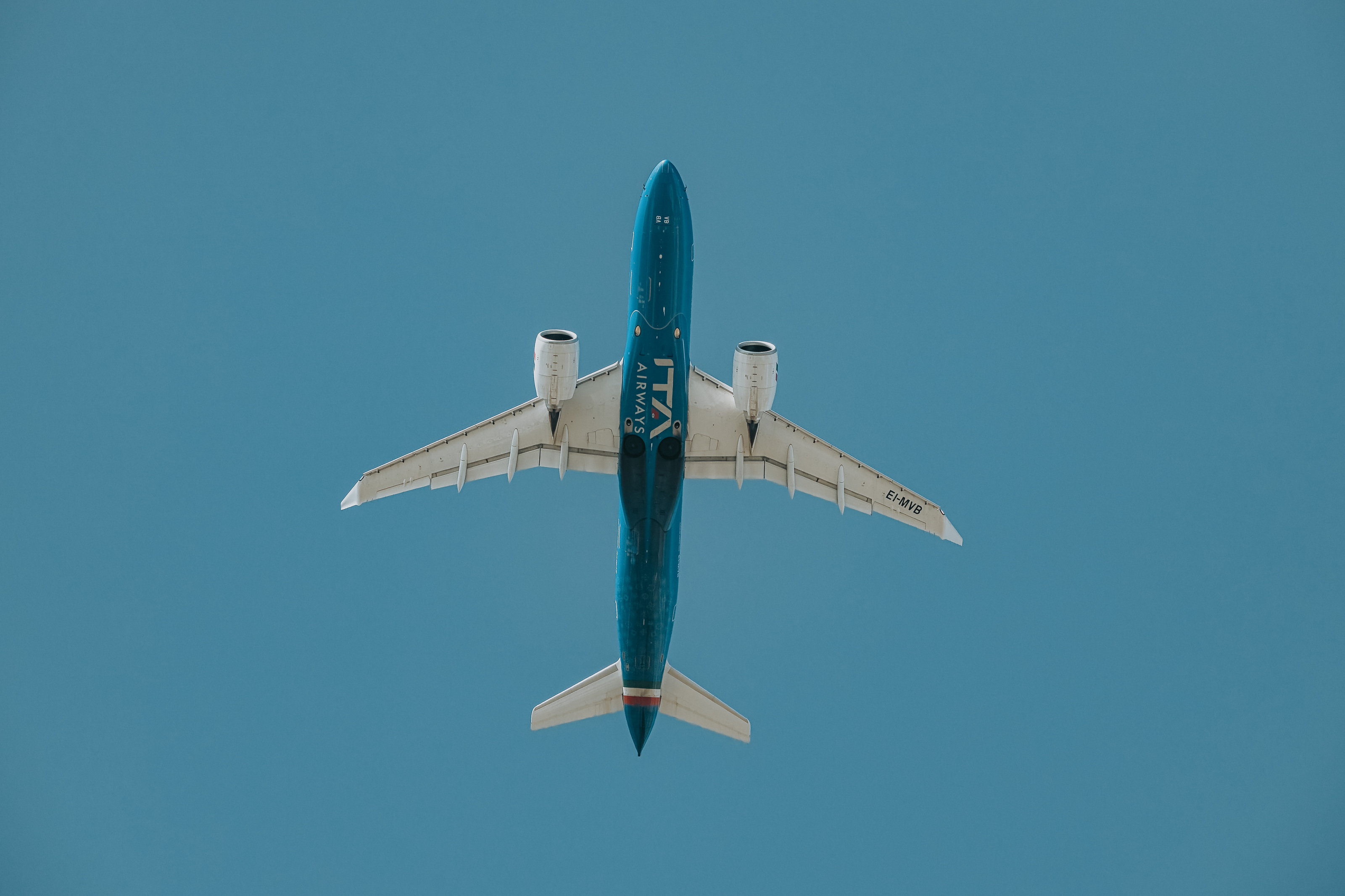 ITA Airways Airbus A220 EI-MVB im Flug, von unten vor blauem Himmel