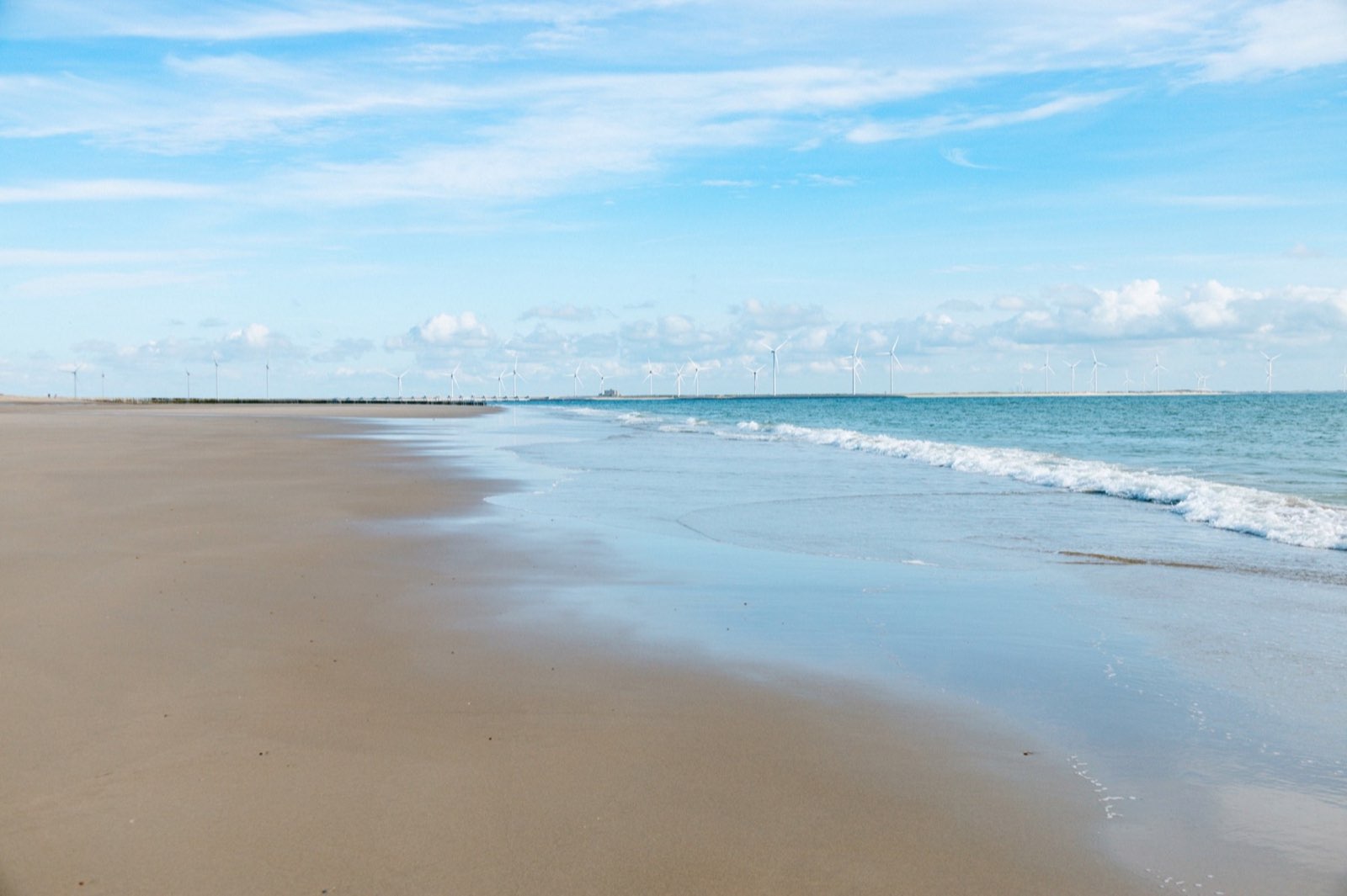 Strand in Zeeland mit Windrädern am Horizont