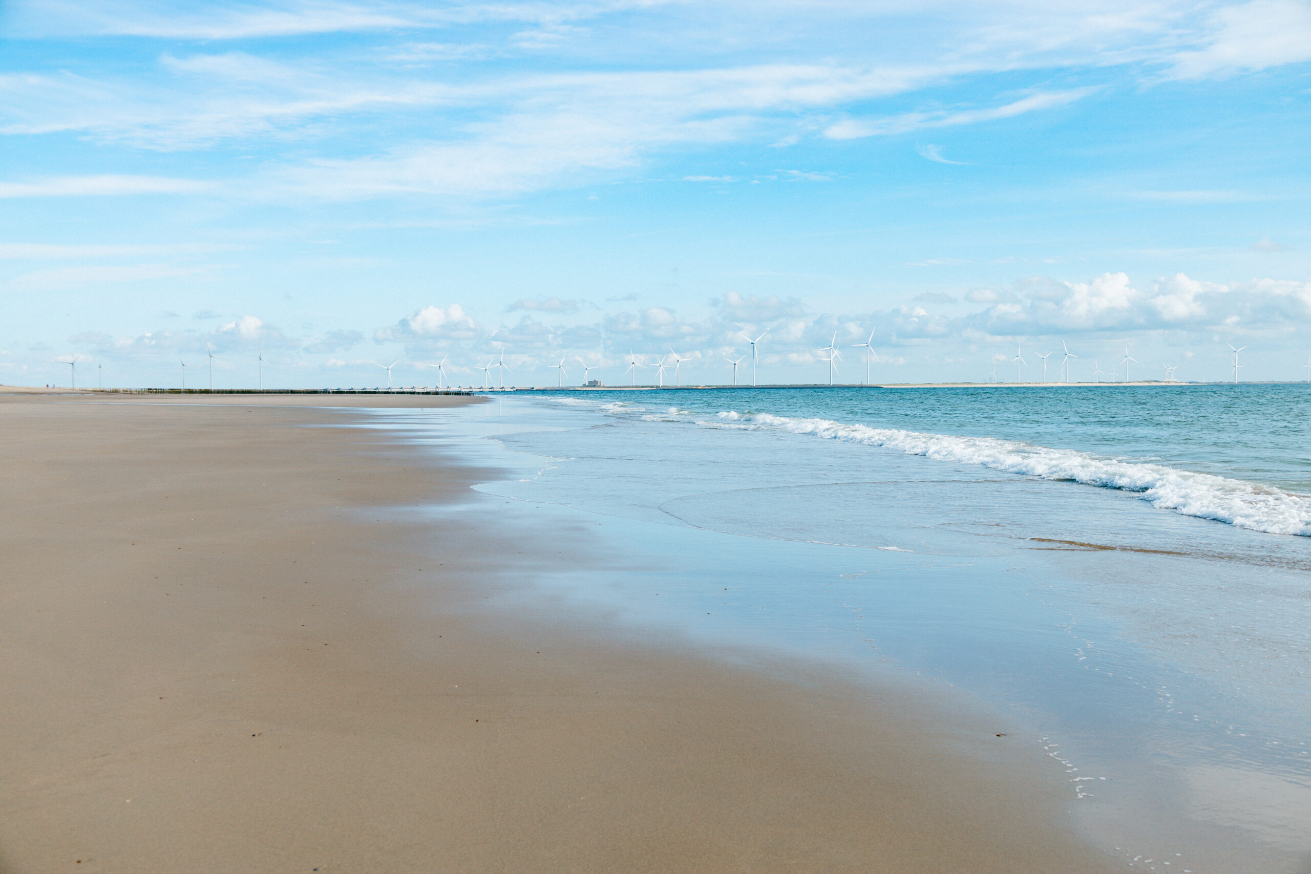 Strand in Zeeland mit Windrädern am Horizont