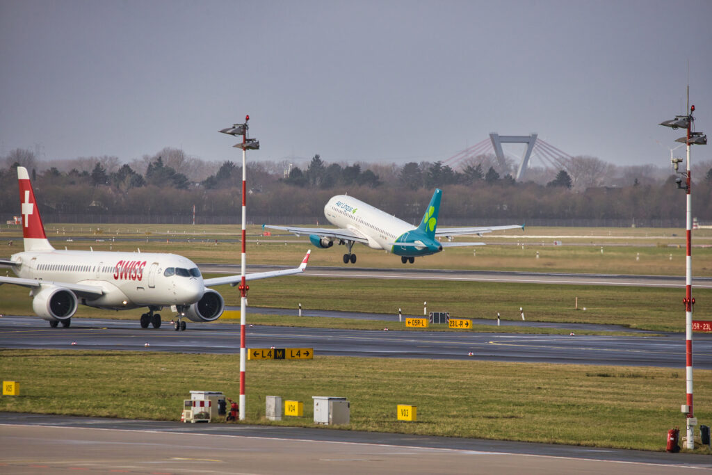 Aer Lingus EI-DEP hebt am Flughafen Düsseldorf ab; eine Swiss-Maschine rollt im Vordergrund.